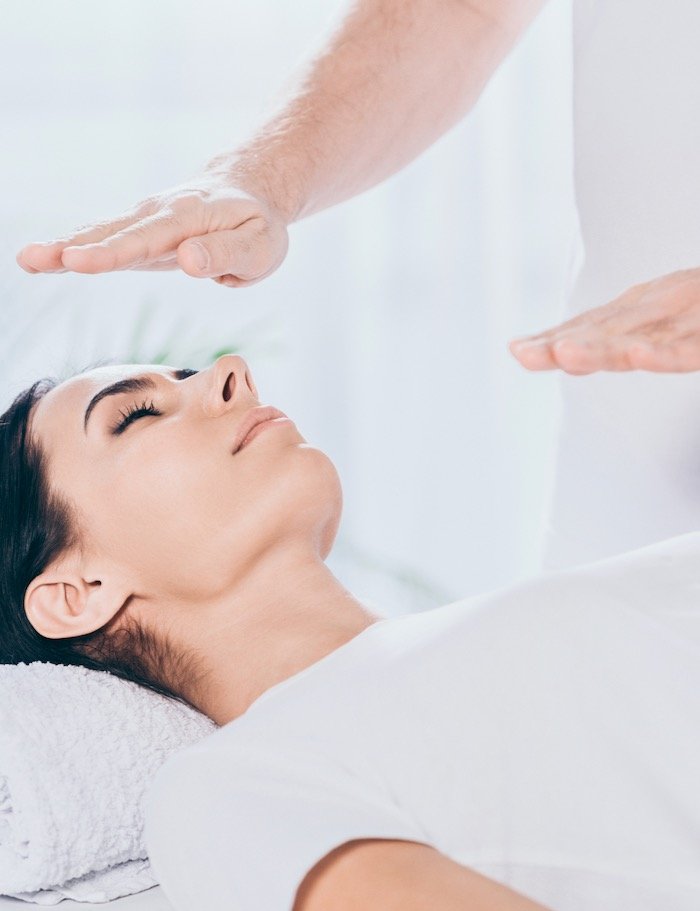 cropped shot of male healer doing reiki healing session to young woman with closed eyes